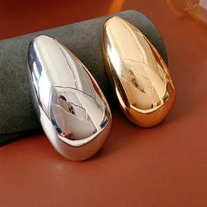 Macro detail of irregular gold and silver water drop brooches with a polished mirror finish