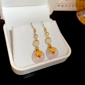 Détail de boucles d'oreilles en calcédoine rose avec glands dorés et perles blanches