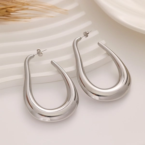 Macro detail of large silver C-shape earrings with a polished mirror finish on wave stand