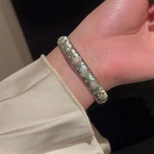 Detail of silver vintage bracelet with star relief and pearl inlay on a model's wrist