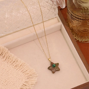 Star-shaped natural stone pendant necklace with gold chain on a wooden jewelry tray