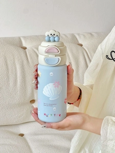 Gourde isotherme bleue pour enfants avec motifs floraux tenue dans un décor cosy