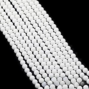 Macro shot of polished white round beads arranged in diagonal rows on black background