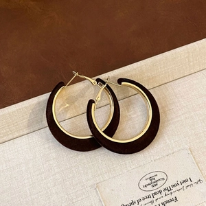 Macro detail of retro C-shaped velvet earrings with gold-toned metal and flocked texture
