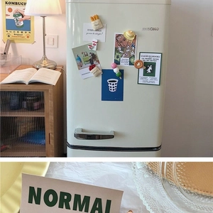 Detailed view of creative food-shaped fridge magnets on a retro cream refrigerator door