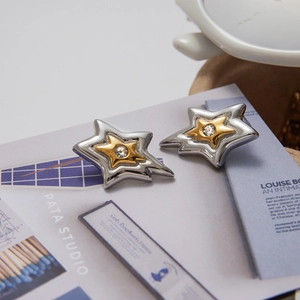 Macro view of two-tone layered star stud earrings with a central sparkling cubic zirconia