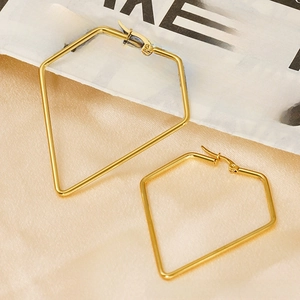 Detail view of gold-plated geometric pentagon hoop earrings on elegant satin fabric