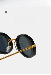 Detailed close-up of retro oval sunglasses with golden metal hinges and soft nose pads