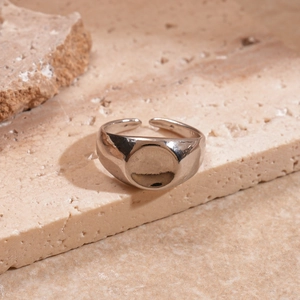 Close-up of a silver irregular open ring on a textured sandstone block in warm lighting