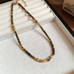 Detail view of vintage tiger eye and pearl beaded necklace displayed on white velvet tray