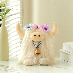 White Highland cow plush toy with floral headpiece and bell on white marble surface