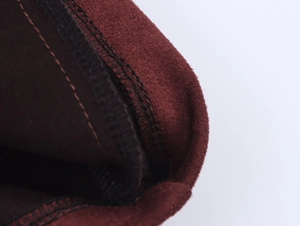 Detailed macro view of dark red suede fabric texture with neat black double stitching
