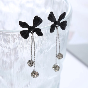 Vue détaillée de boucles d'oreilles à pompons longs avec nœud noir et cristaux de zircon