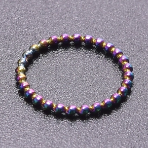 Macro view of iridescent beaded ring with rainbow metallic finish on a textured surface