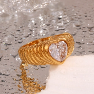 Macro view of wide 18K gold plated ring featuring a heart zircon and embossed stripes with water