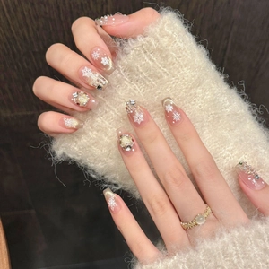Detail of glitter cat eye press-on nails with white snowflake and rhinestone accents