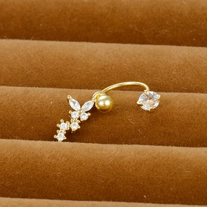 Macro shot of gold navel ring with butterfly and flower zircon inlay on brown suede