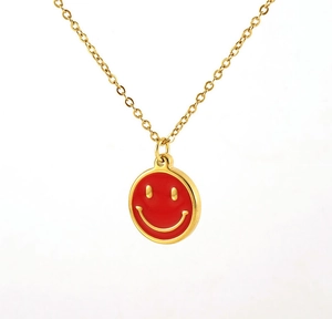 Detail of 18K gold-plated necklace featuring a round red enamel smiley face pendant