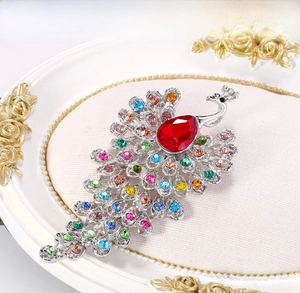 Detail of peacock brooch with red teardrop gem and colorful rhinestones on silver base