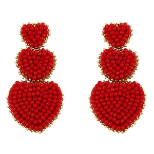 Close-up of triple-layered red heart drop earrings with intricate beaded texture