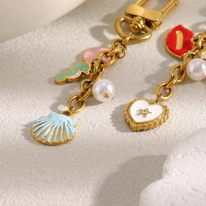 Vue macro de bijoux de sac dorés 18K avec motifs marins en émail et perles élégantes
