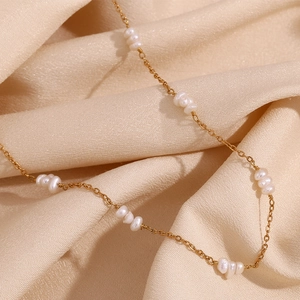 Détail macro de la chaîne perlée plaquée or 18 carats et perles baroques sur soie champagne