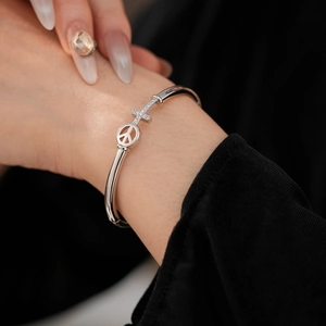 Detail of silver bangle featuring a peace sign and cross pavé with sparkling crystals