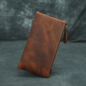 Close-up of vintage brown crazy horse leather texture on a slim zipper wallet pouch