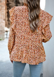 Vista posteriore di una donna con camicetta di chiffon arancione a fiori e maniche a volant