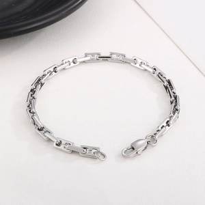 Macro view of silver rectangular chain links with lobster clasp on textured background