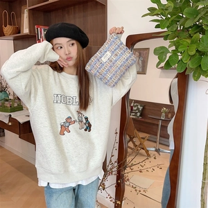 Close-up of a blue tweed textured cosmetic pouch and grey cartoon sweatshirt