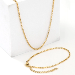 Polished gold stainless steel box chain necklace and bracelet set on white background