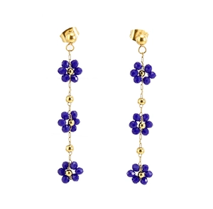 Détail rapproché de boucles d'oreilles bohèmes en or 18K avec fleurs en cristal bleu