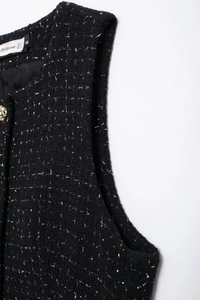 Détail du gilet en tweed noir avec fils d'argent entrelacés et accent bouton doré chic