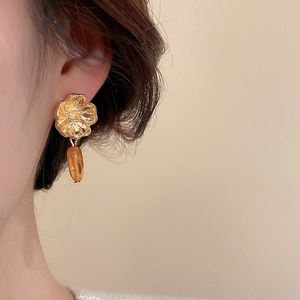 Gros plan sur des boucles d'oreilles vintage en résine dorée portées par un mannequin