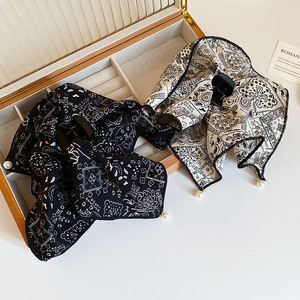 Detail of silk-texture paisley bow hair clips with pearl drops in a wooden box