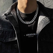 Close-up of a silver Cuban link chain necklace worn over a black denim jacket