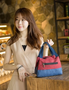 Detail showing the red and blue canvas lunch bag with front zipper pocket and sturdy handles
