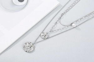 Detail of silver layered necklace with pearl pendant and hammered round metal discs