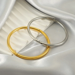 Minimalist polished stainless steel bangles in gold and silver finish on white silk