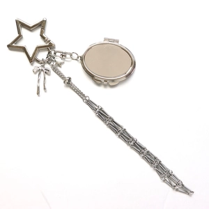 Detail of silver star keychain with bow pendant, folding mirror, and long chain tassel