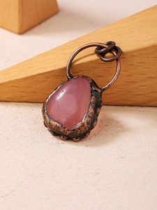 Detail of vintage copper wrapped irregular pink gemstone pendant with handmade texture