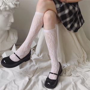 Close-up of white lace knee-high socks with floral patterns and ribbed cuffs for girls