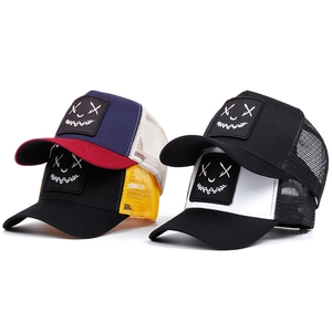 Detailed view of four colorful mesh trucker hats with trendy demon smiley face embroidery
