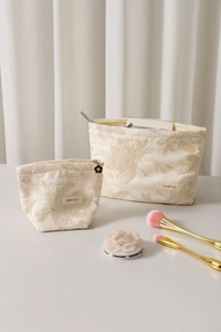 Détail de broderie sur trousse de maquillage en lin crème avec pendentif fleur