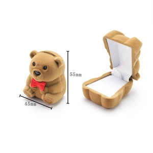 Detailed view of bear-shaped brown velvet jewelry box with a red bow and white interior
