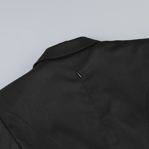 Detail of a sleek black blazer featuring a precise back seam with a high-quality zipper