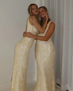 Detail of the backless design and floral lace fabric on a slim fit yellow maxi dress