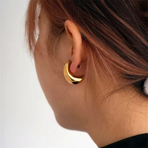 Detail of gold crescent hoop earrings on model featuring a polished mirror finish surface