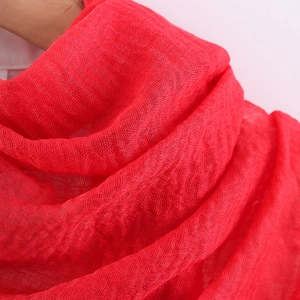Detail shot of solid red pleated cotton linen scarf featuring frayed edges and bubble texture